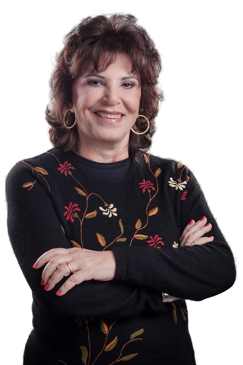 Maria Tereza Jorge Pádua, sorrindo, de braços cruzados